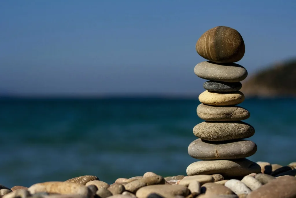 Balanced stack of smooth pebbles on a beach with the sea in the background.