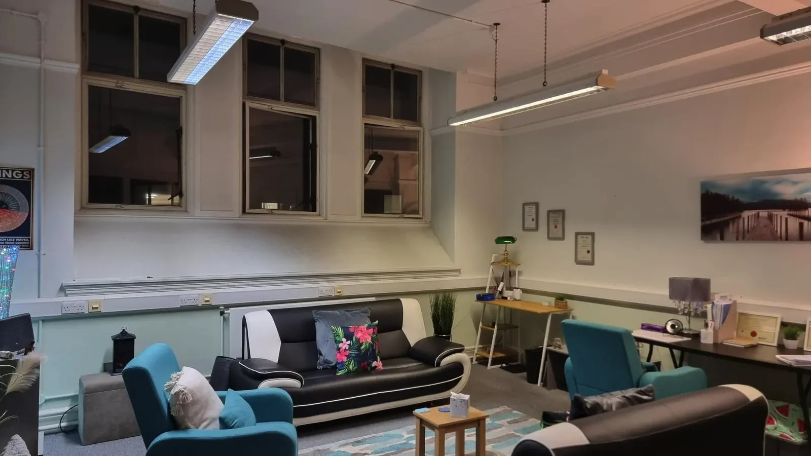 Cosy therapy office with a sofa, armchairs, and soft lighting. Certificates and calming decor on the walls.